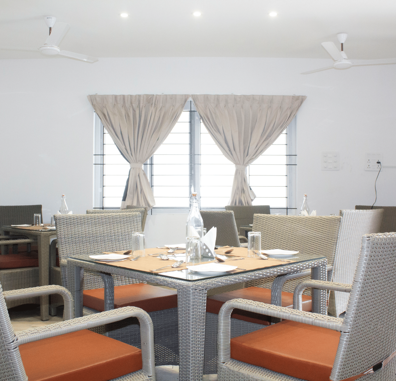 A close-up shot of a well-arranged dining table with 4 chairs kept around it at the Spice and Slice Restaurant at WOW Naturefull Resorts, Yercaud.