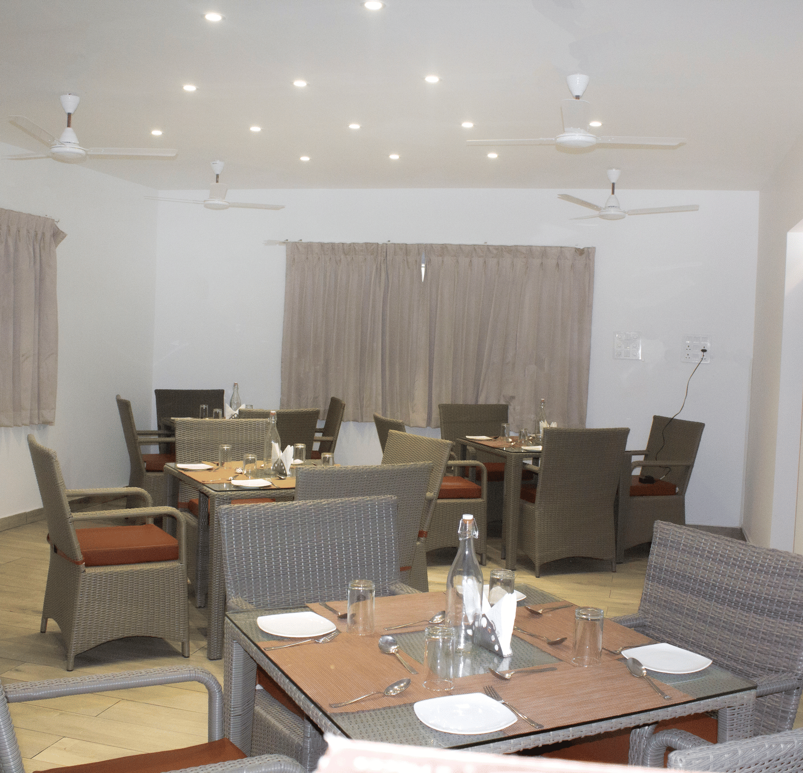 The Spice and Slice Restaurant with dim lighting along with 4 fans hanging from the ceiling at WOW Naturefull Resorts, Yercaud.