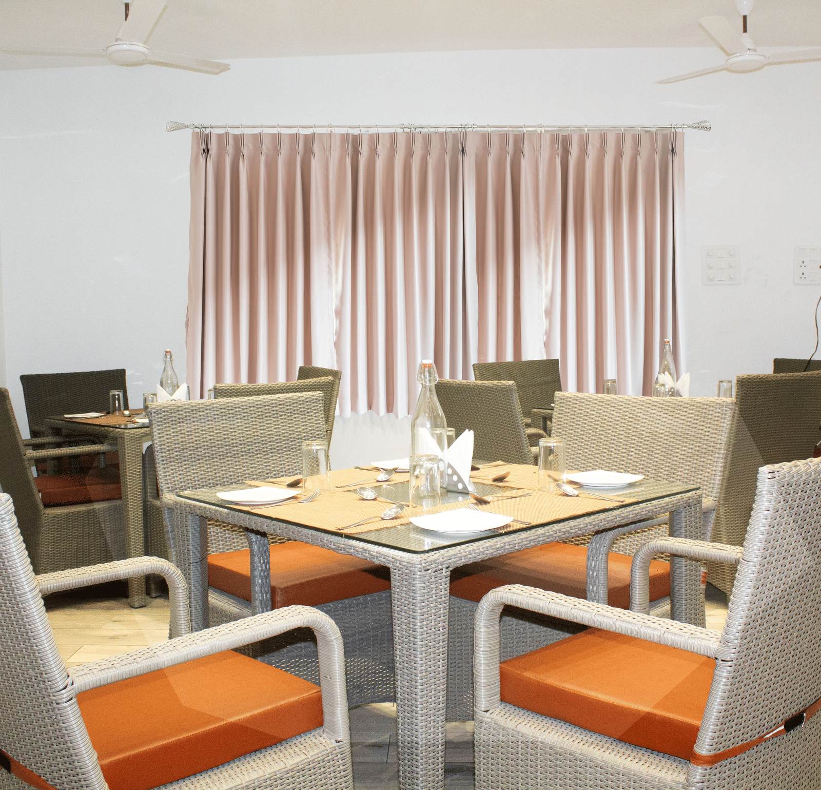 A dining table with orange-coloured cushions on the chair at the Spice and Slice Restaurant at WOW Naturefull Resorts, Yercaud.
