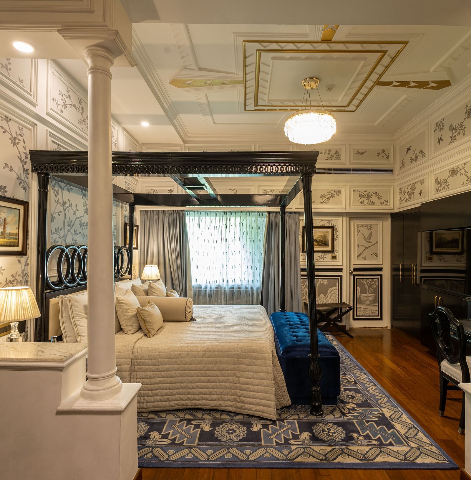Grand Luxury Room at The Claridges New Delhi, showcasing a side view of the canopy bed with a bedside lamp and a chandelier
