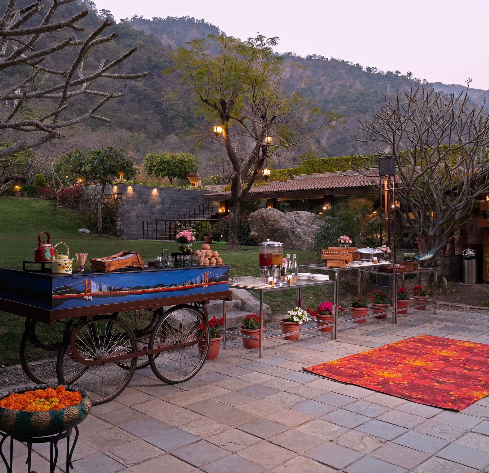 Food at outdoor food stations. There are mountains in the background and lush surrounding the scene.