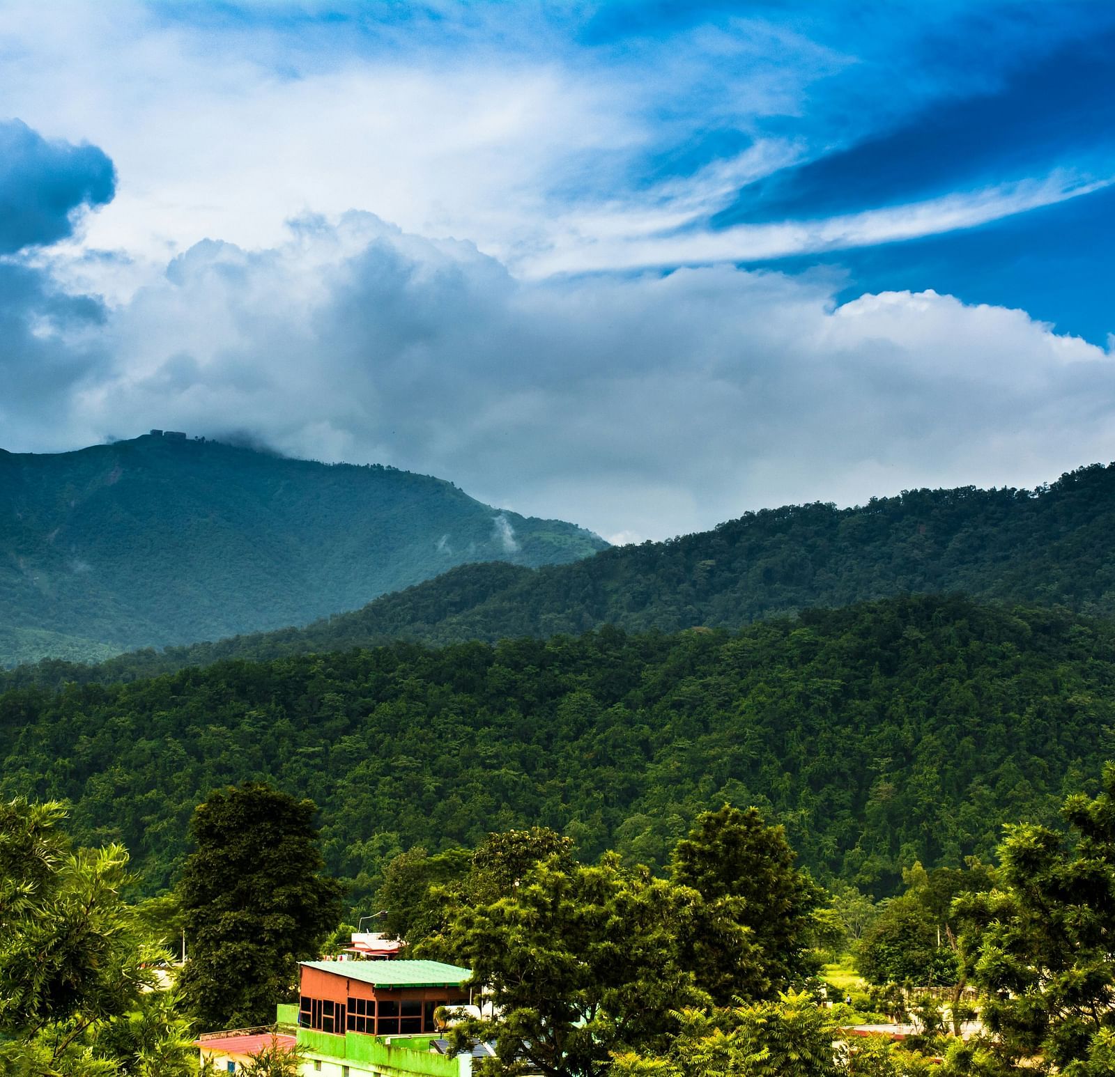 A wide view of mountains with a sky with scattered clouds in the background