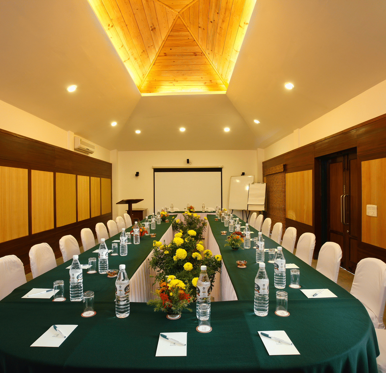 Conference hall with arranged chairs and projector at baikunth Resort, Kasauli 