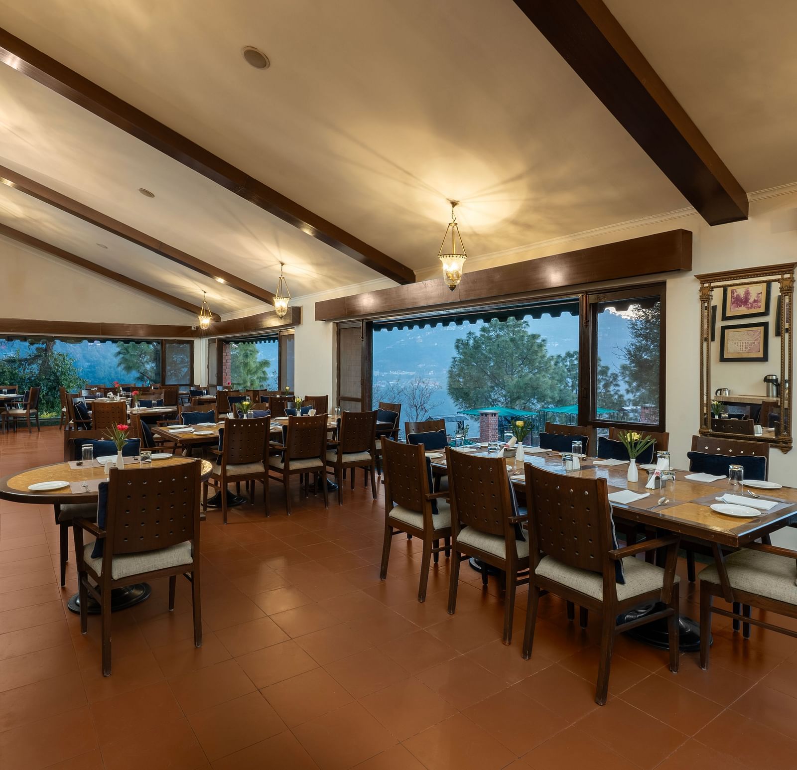 Restaurant area during evening time with lights on  fully wooden furnished with a beautiful view at Baikuth resort, kasauli.