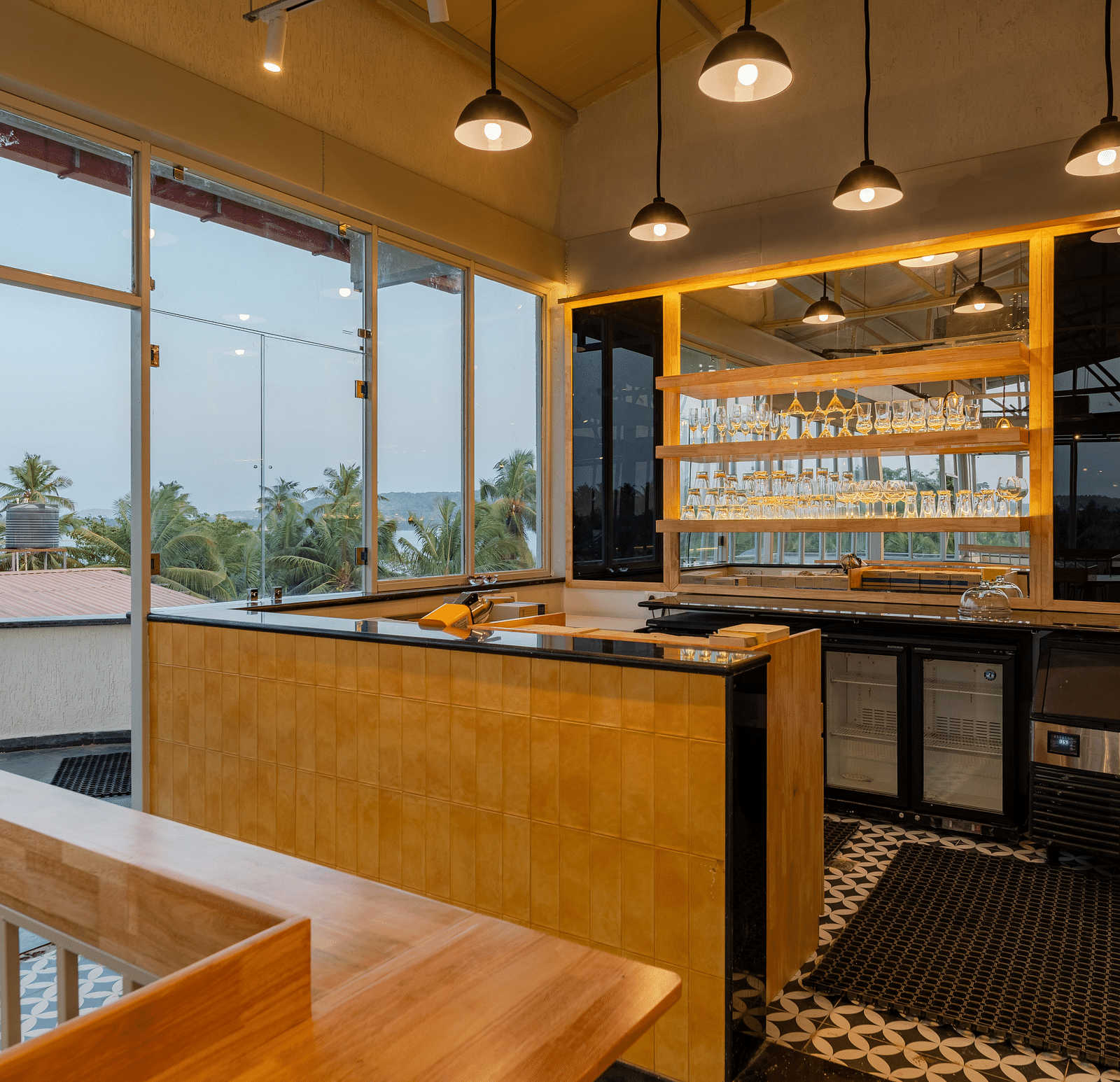 Interior of a contemporary cafe with bar stools and a window view. at Bedzzz Xclusiv Morjim, Goa