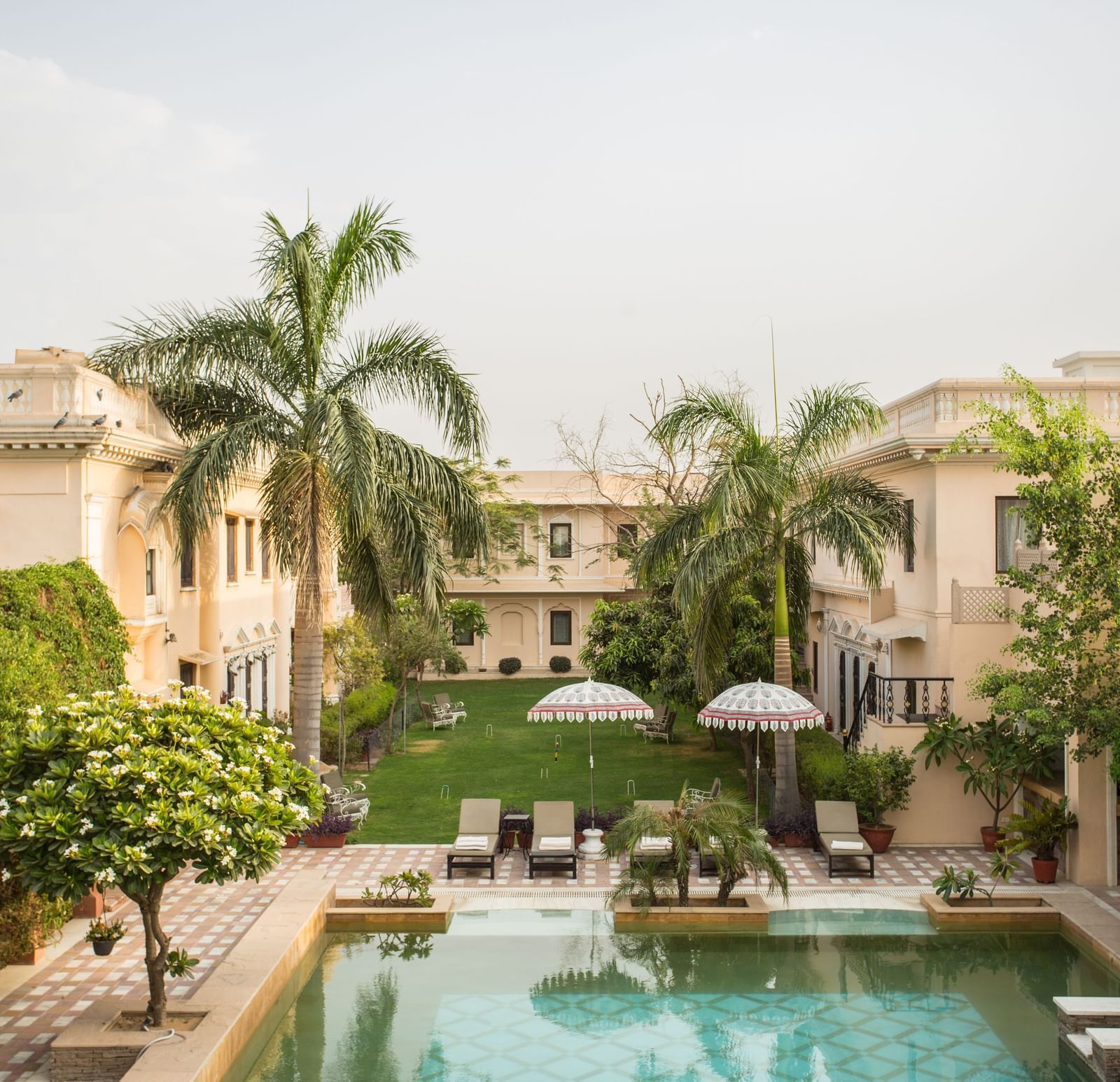 An outdoor scene features a swimming pool in front of Royal Heritage Haveli with palm trees.