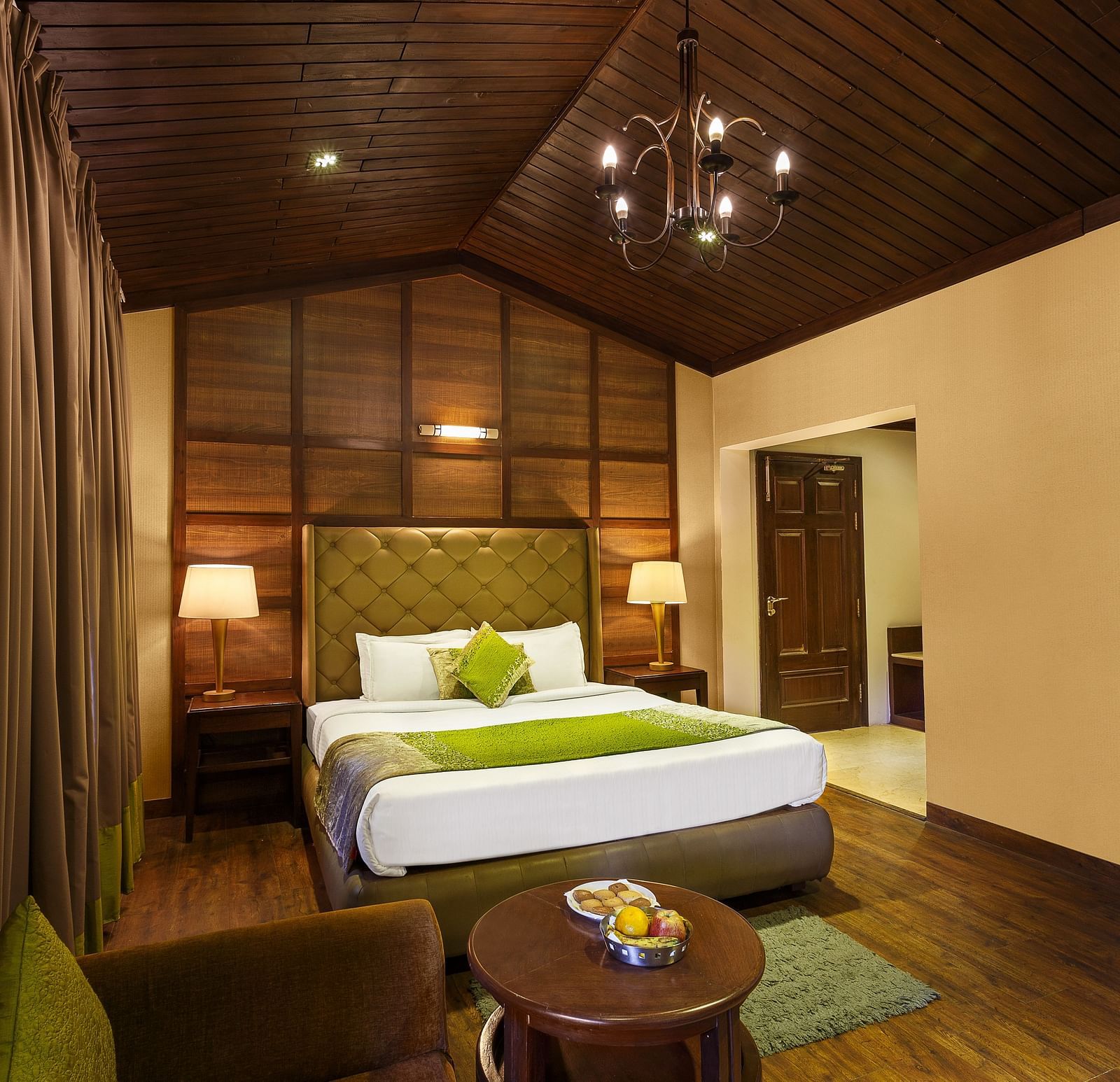 a bedroom with a large bed and side lamps, a table and a sofa - The Earl's Court, Nainital