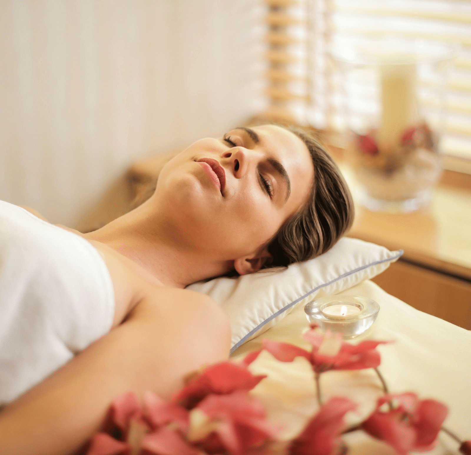 A woman lying on her back on a spa bed, enjoying spa treatments.