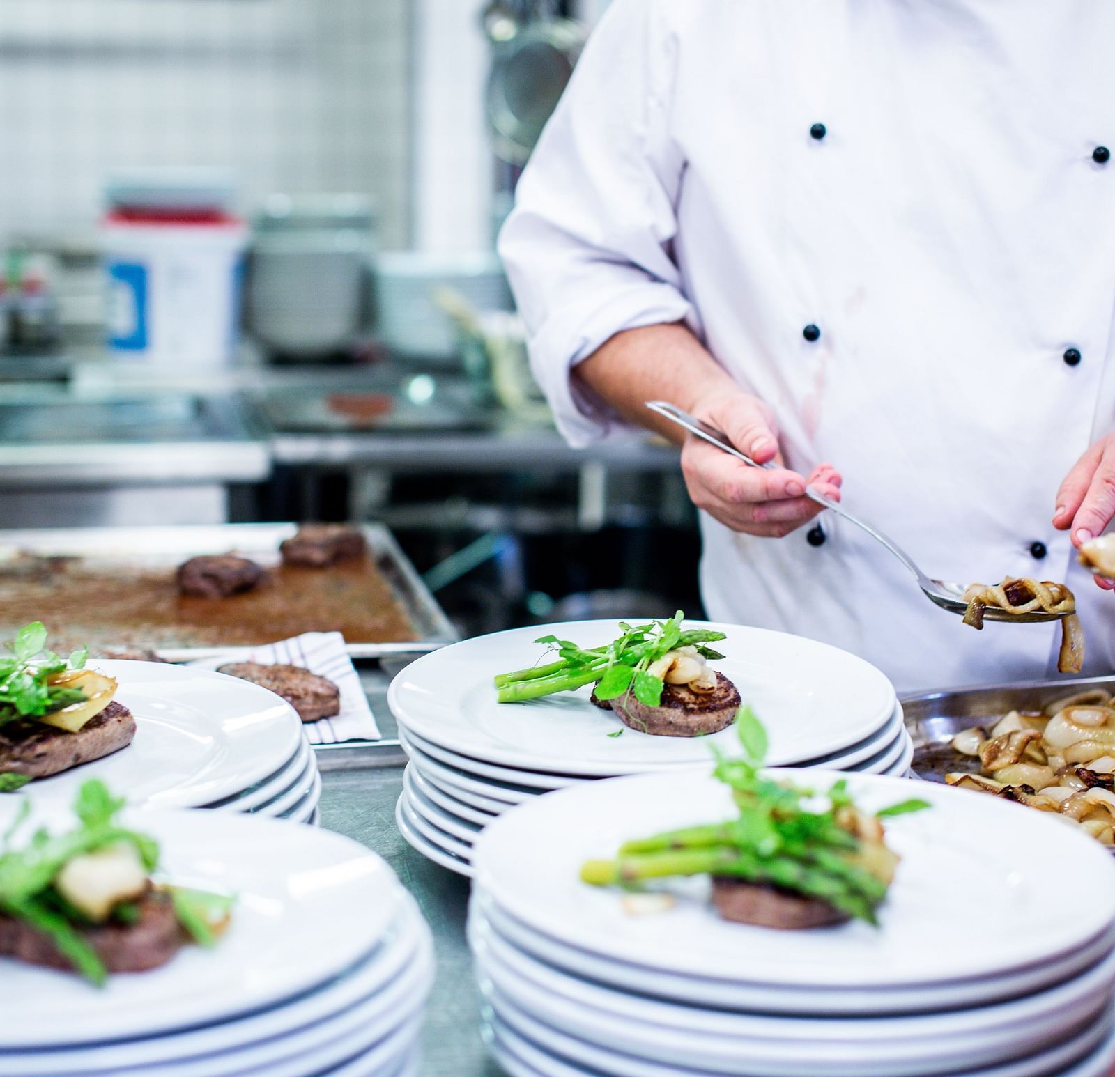 An image of a chef serving dishes in plates inside the kitchen