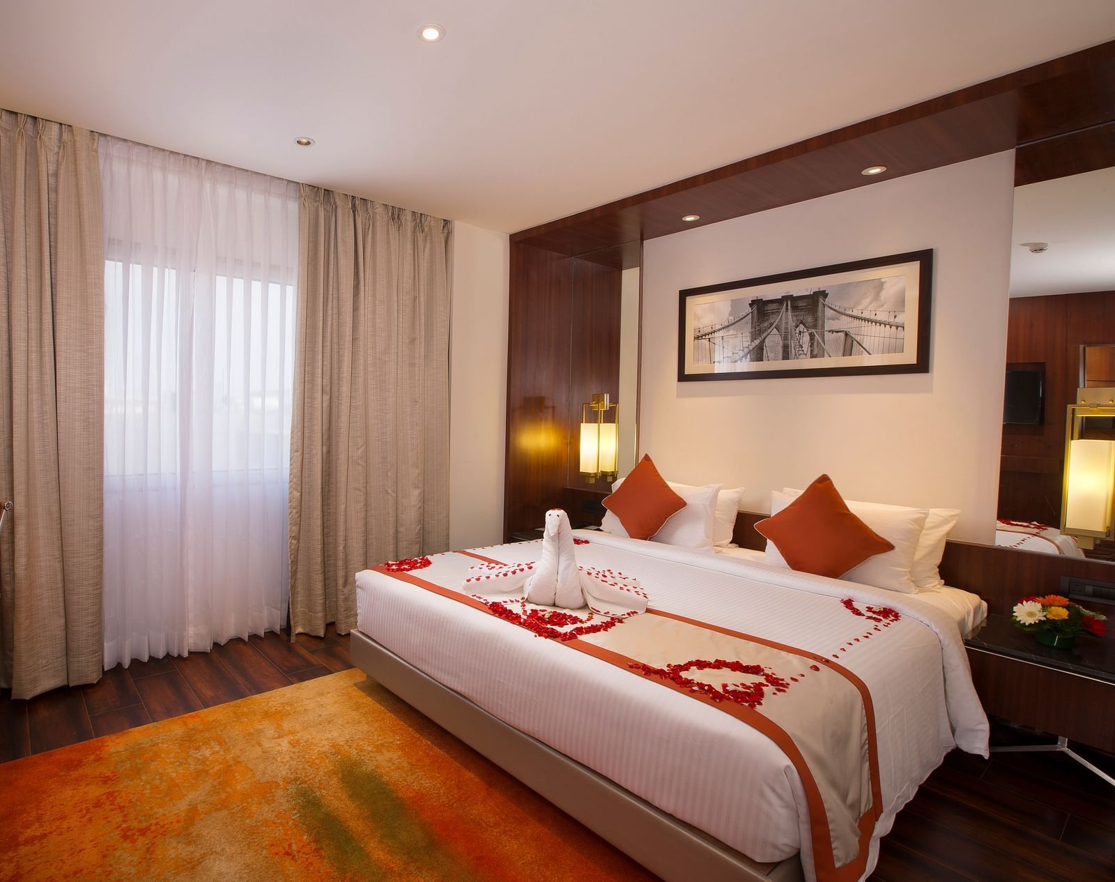 A hotel room with a large bed with white and orange linens, a brown office chair and sheer curtains over a window - Hotel Southend by TGI - Bommasandra, Bangalore