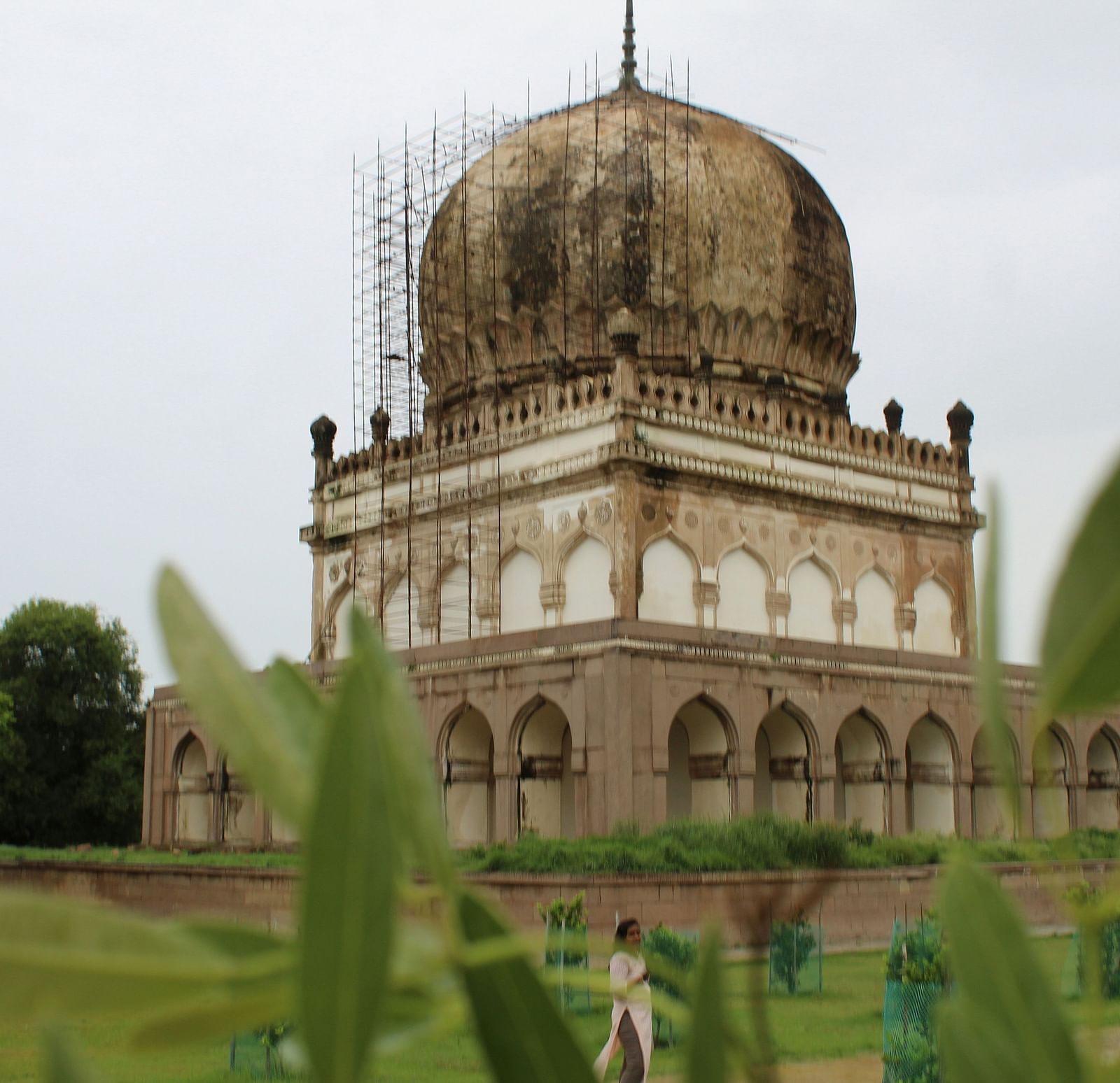 An overview of Qutub Shahi Tomb with a person walking in front of the monument.