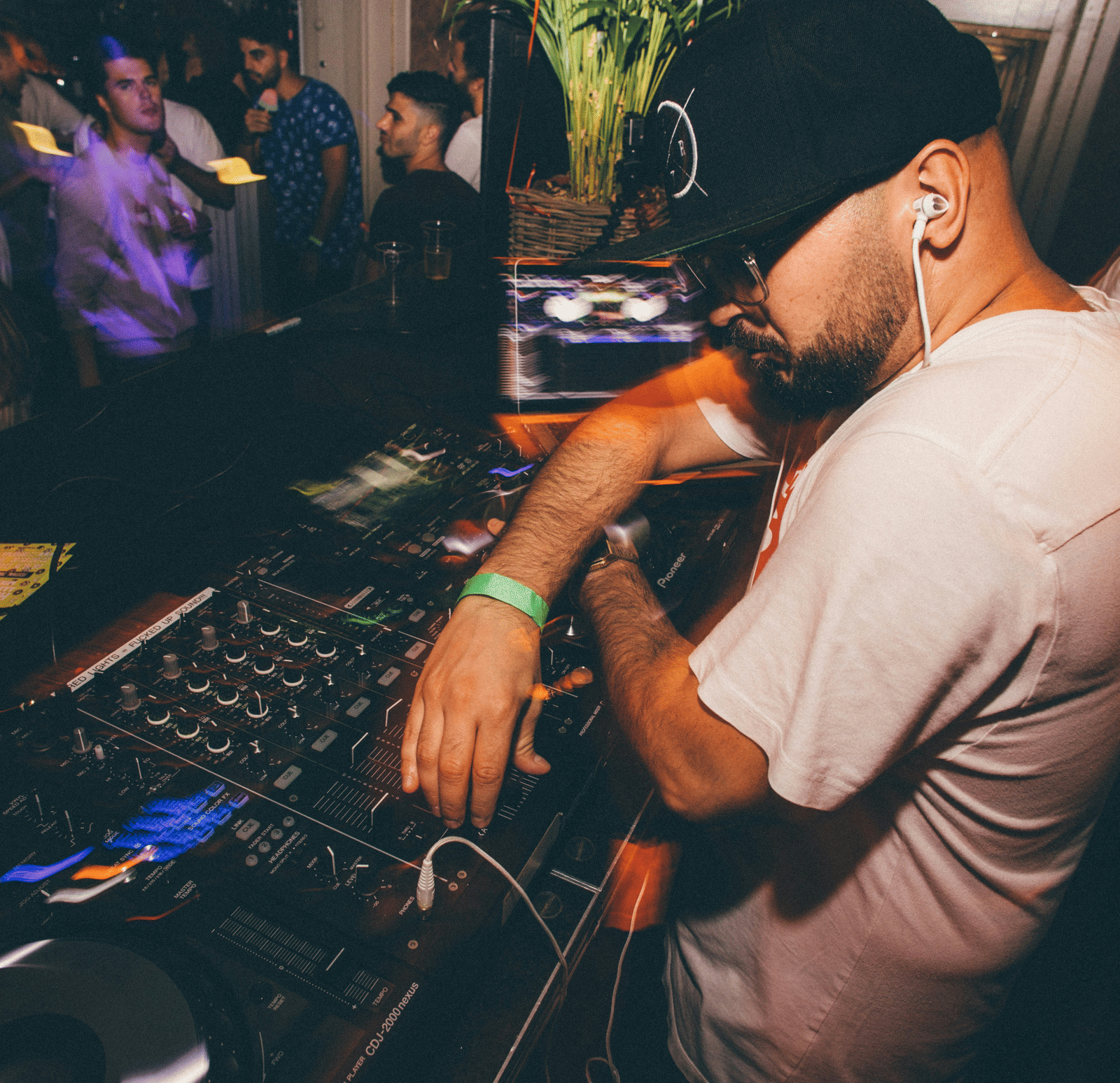 A close up of a DJ playing his DJ setup for a crowd of people.