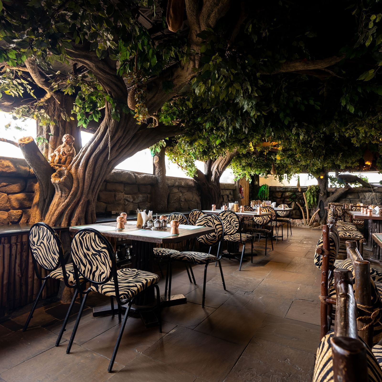 Seating arrangements inside a restaurant with trees on the side at Hotel Pai Vista, Mysore