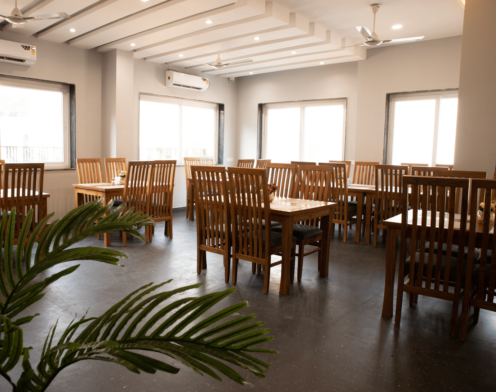 A dining area with tables, chairs, and a potted plant at Perfectstayz Premium Laxmi Heritage.