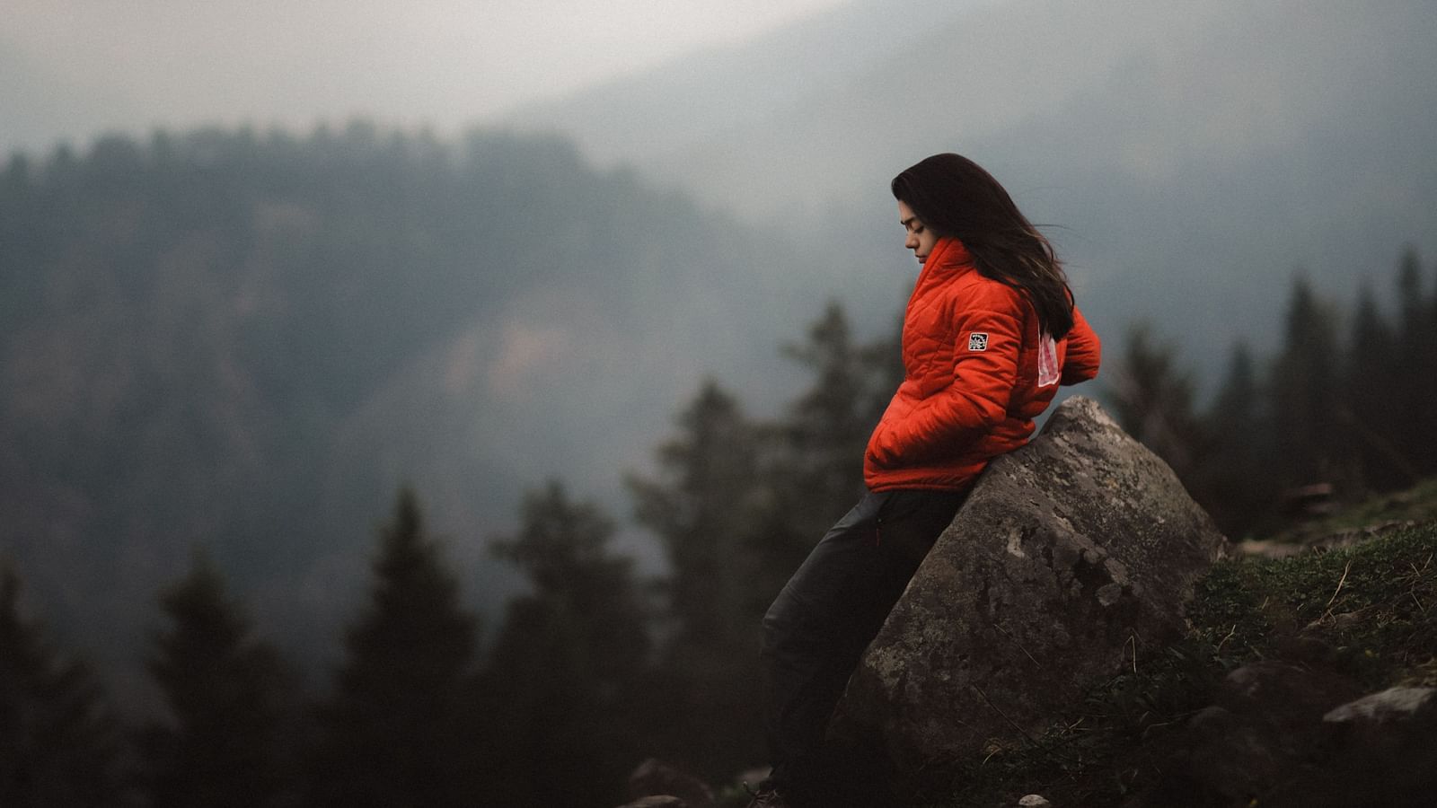 a solo woman traveller posing for a picture on top of mountain