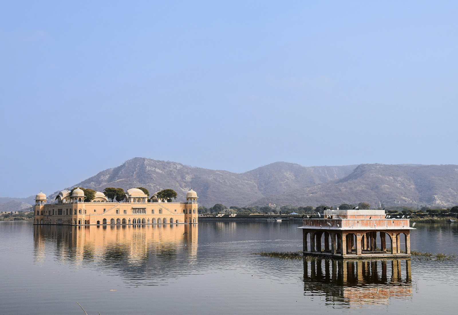a beautiful image of the jal mahal in the middle of a lake in jaipur with mountains in the background