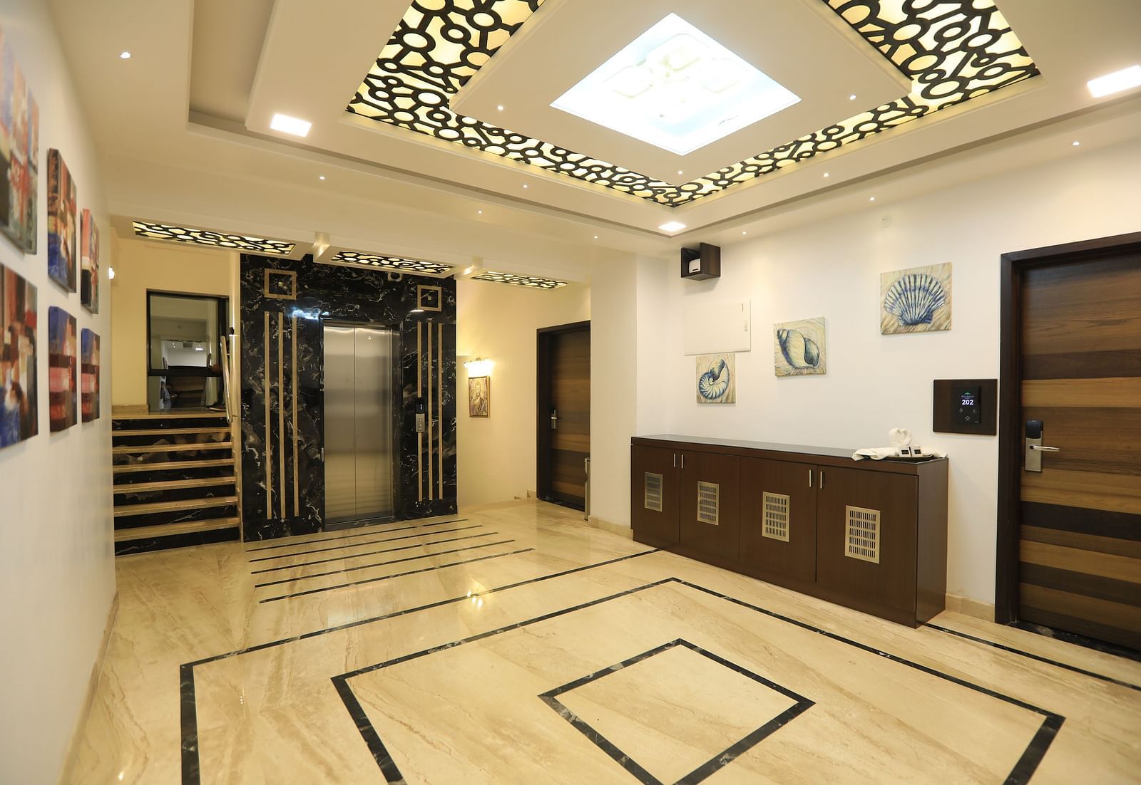Image of a hall with a table on the side and lights on the ceiling at Hotel Altitude, Madikeri.