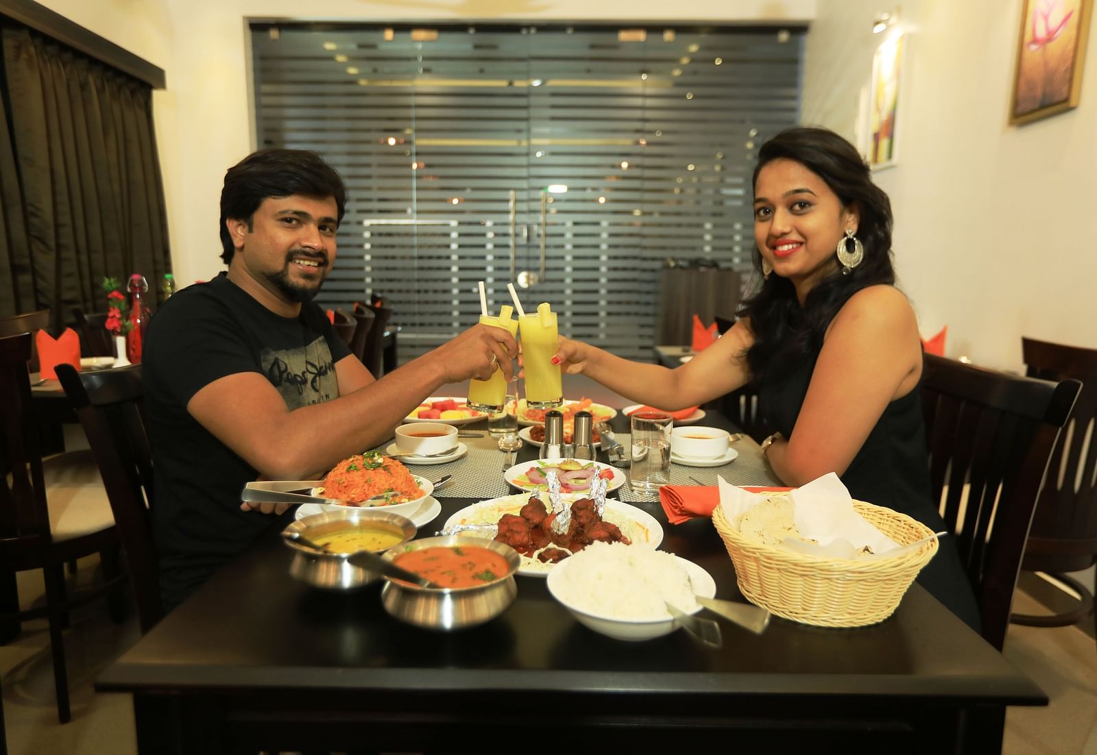 Image of a man and a woman holding up glasses of drinks at Hotel Altitude, Madikeri.