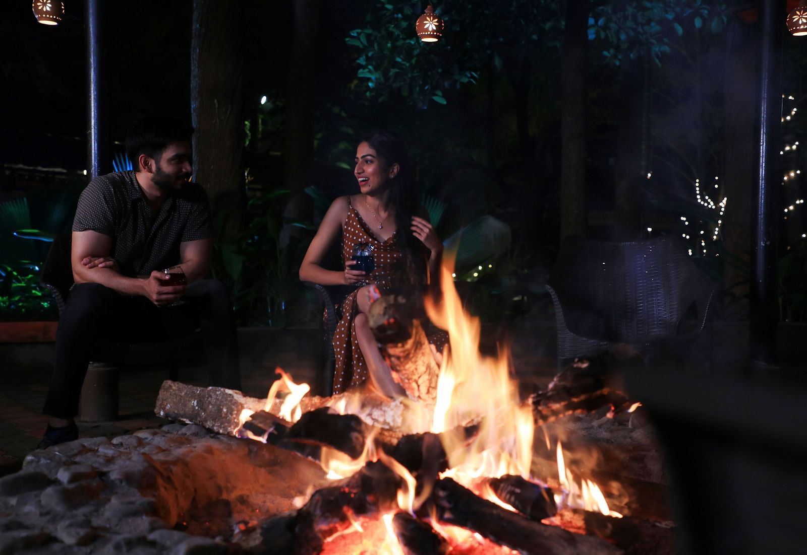 Image of two people sitting beside a bonfire at Parampara Resort & Spa, Kushalnagar.