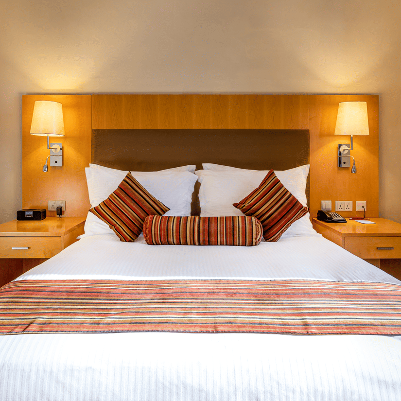 A suite featuring a double bed with striped accents, ambient lighting, and wooden furnishings—perfect for travellers seeking elegant suites in Addis Ababa.