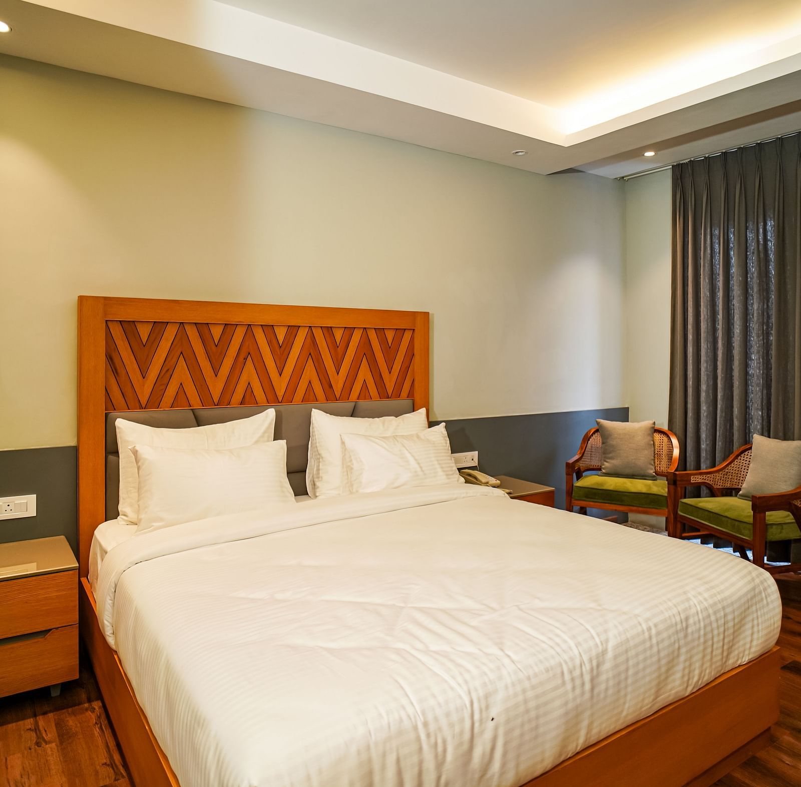 A well-appointed hotel room with a large bed, bedside tables with lamps, and a comfortable seating area | Deluxe Room | Sukama Resort & Spa, Nainital
