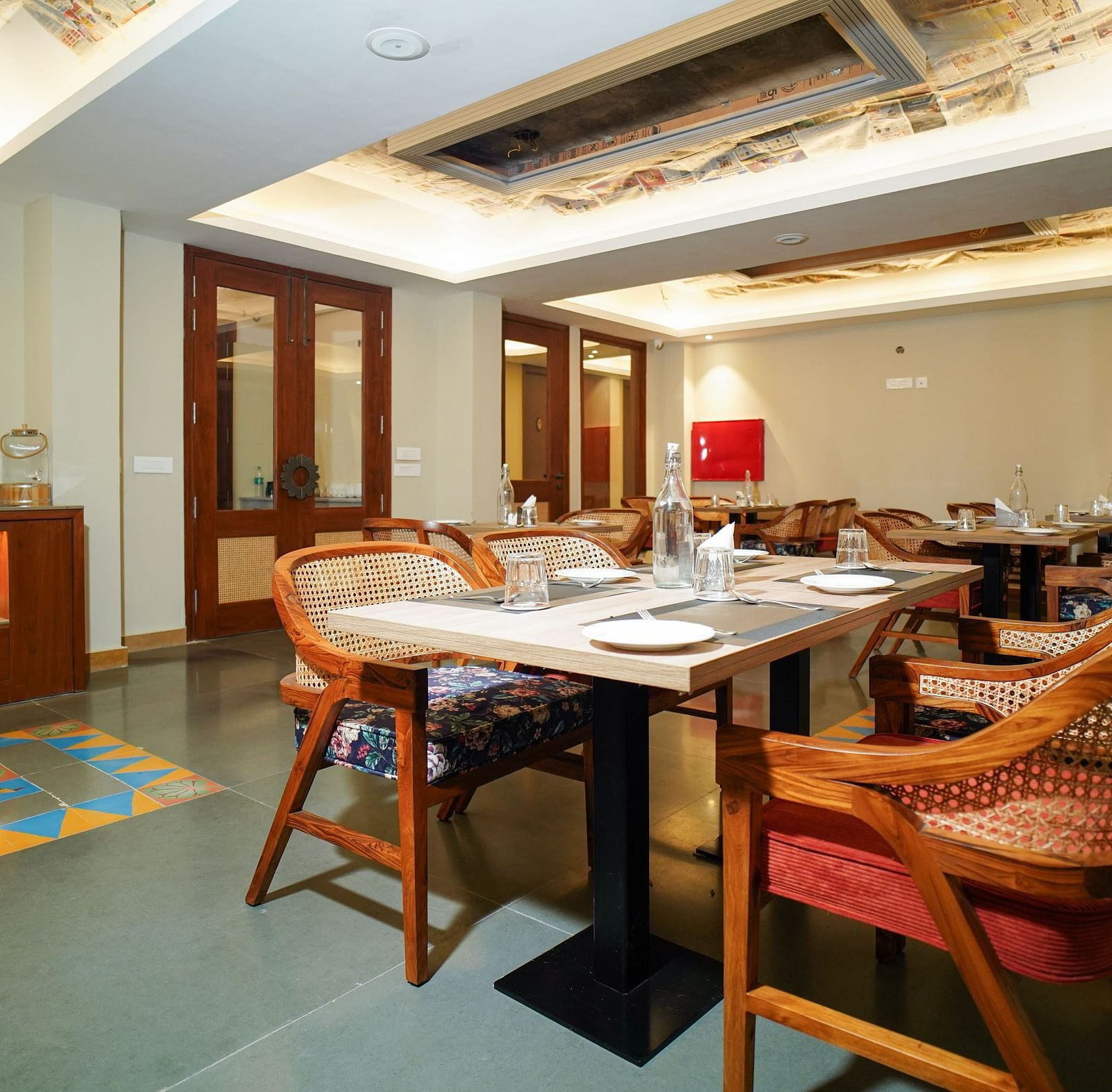 A dining room with several tables and chairs, a fireplace, and a large window | Sukama Resort & Spa, Nainital