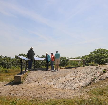 Visitors standing near a stone structure on a grassy hill near Hartstone Inn.