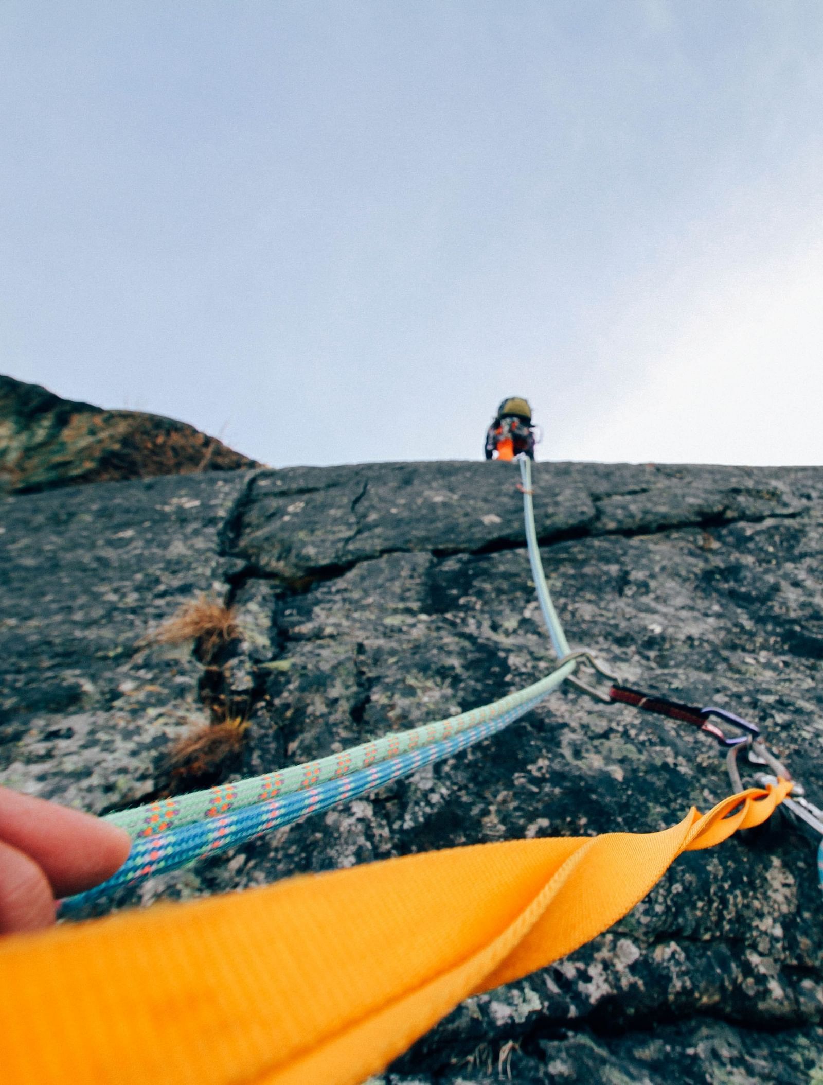 image of a person climbing a mountain cliff holding on to climbing ropes 