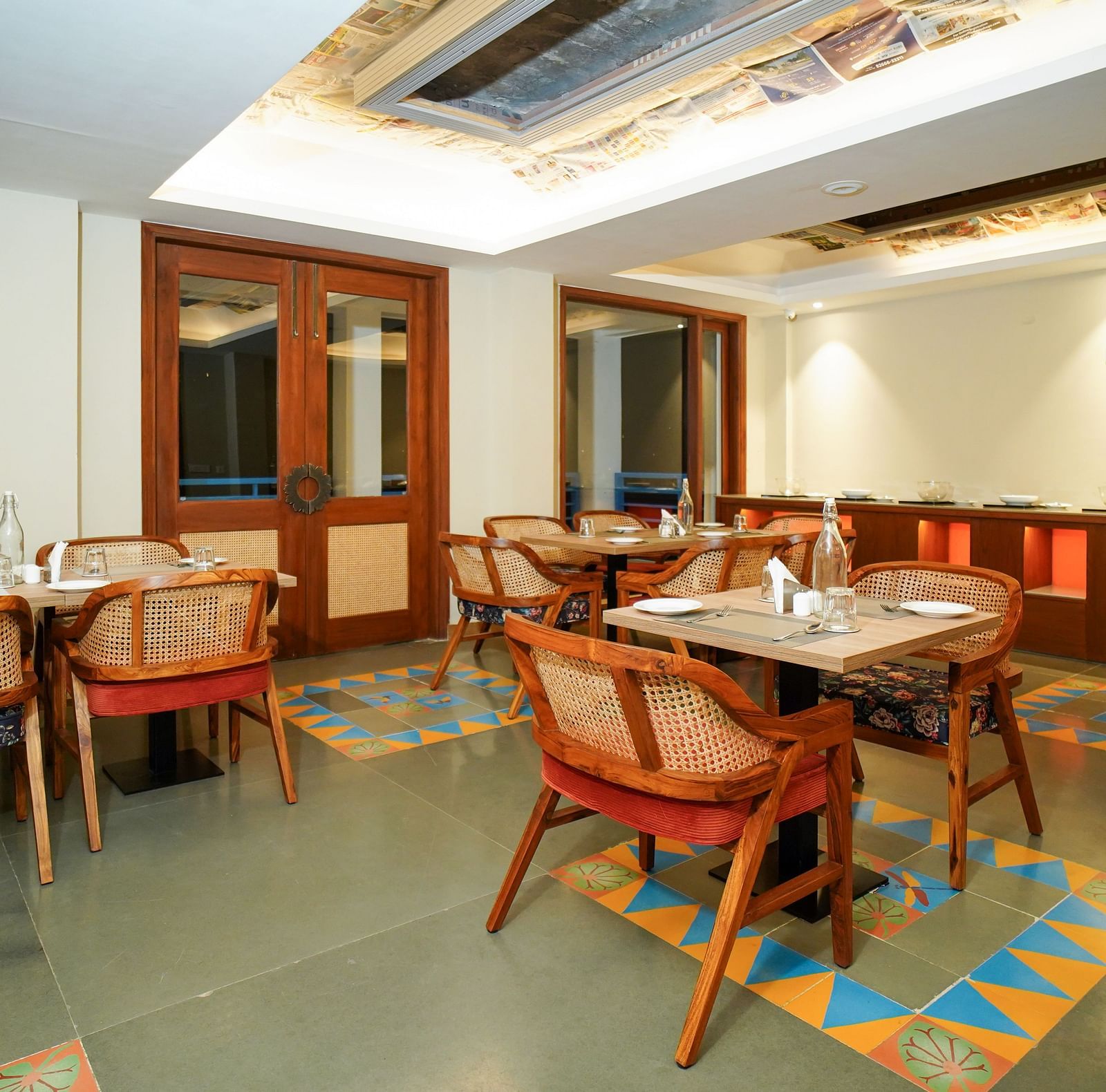 A dining area with multiple tables and chairs, featuring wooden accents and a patterned ceiling | Sukama Resort & Spa, Nainital