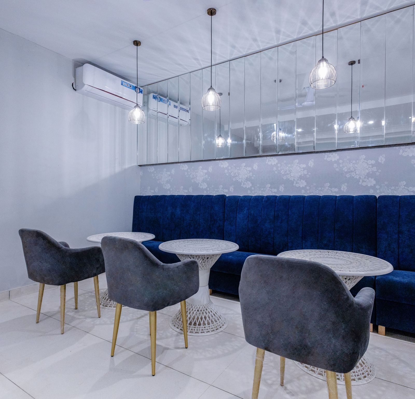 Corner view shot of the restaurant with three round tables with a huge blue couch in front of it - Hotel Downtown17, Chandigarh.