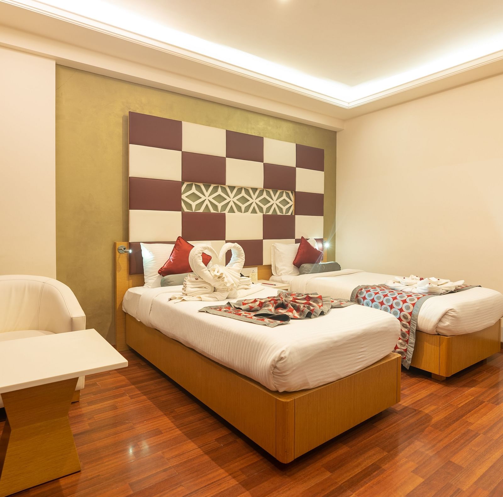 A room with twin beds and a sofa at The President Hotel, Hubli