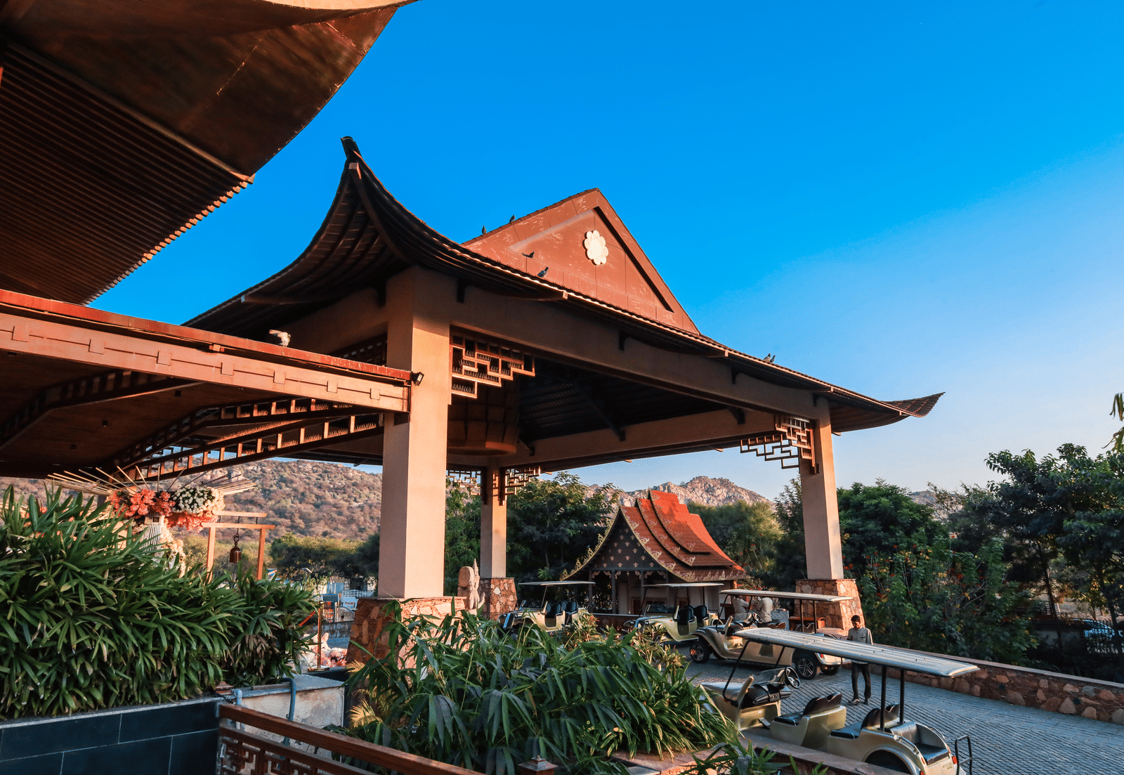 The exterior entrance of Ananta Spa & Resort, Jaipur, showcases its distinctive pagoda-style architecture against a bright blue sky.