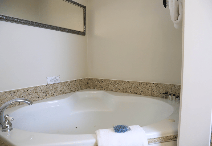 A jacuzzi tub with granite tile, towels, and amenity bottles
