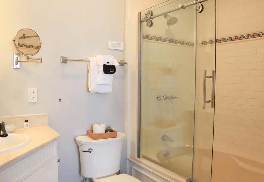 A standard hotel bathroom with a glass-enclosed shower, white toilet, and tan countertop