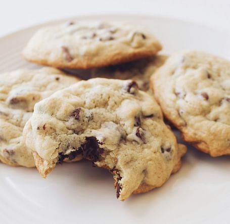 A few chocolate chip cookies placed on a white plate.