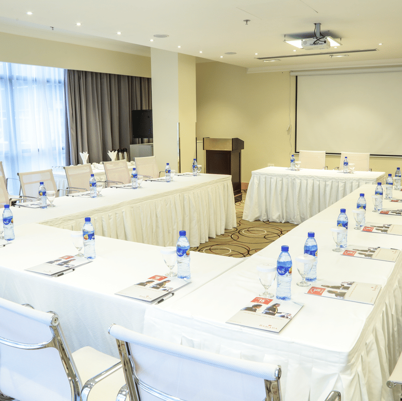 An overview of a business centre with a U-shaped table having water bottles and many chairs in view - Ramada by Wyndham Addis, Addis Ababa.