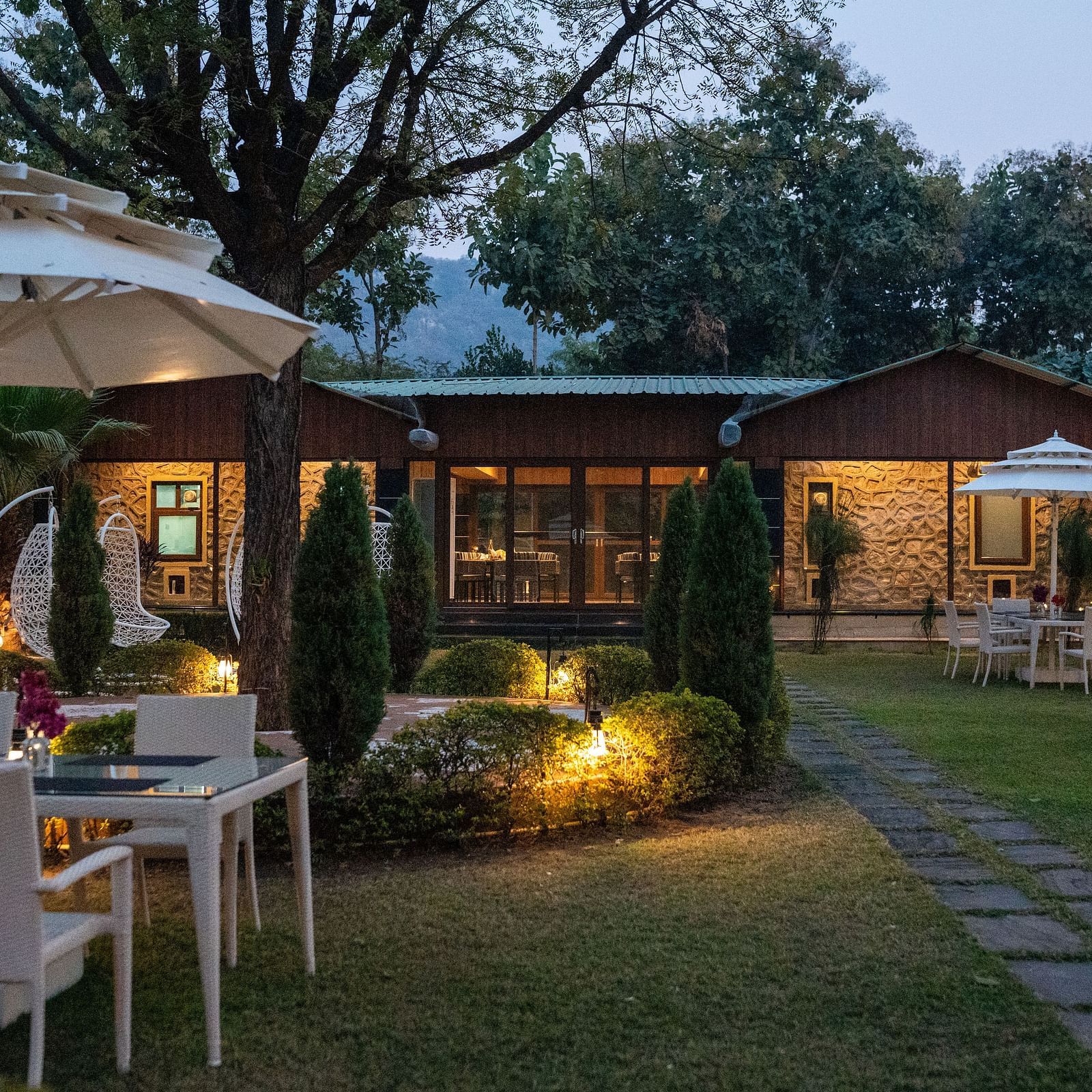 An evening view of the illuminated outdoor dining area at Aamaghati Jungle Retreat Ranthambore.