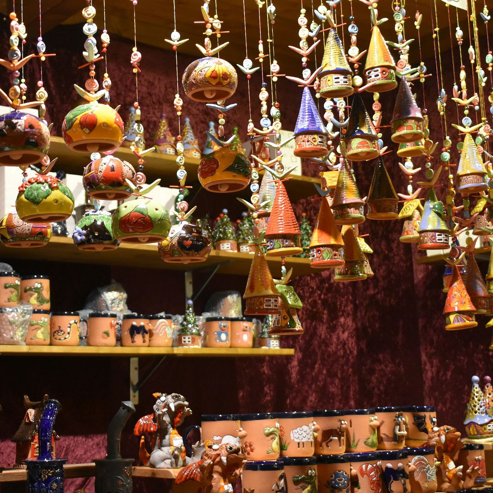 Display of colourful handcrafted pottery and hanging ceramic decorations in a vibrant store setting.