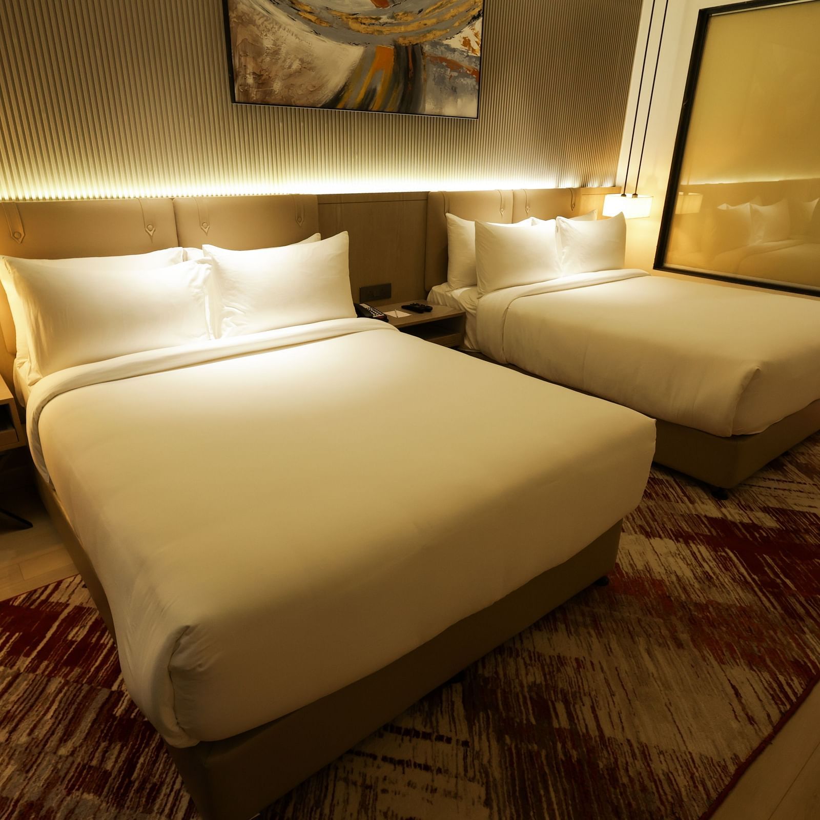 Warmly lit bedroom with wooden furnishings and red-patterned carpet at Ramada by Wyndham Sonipat Murthal