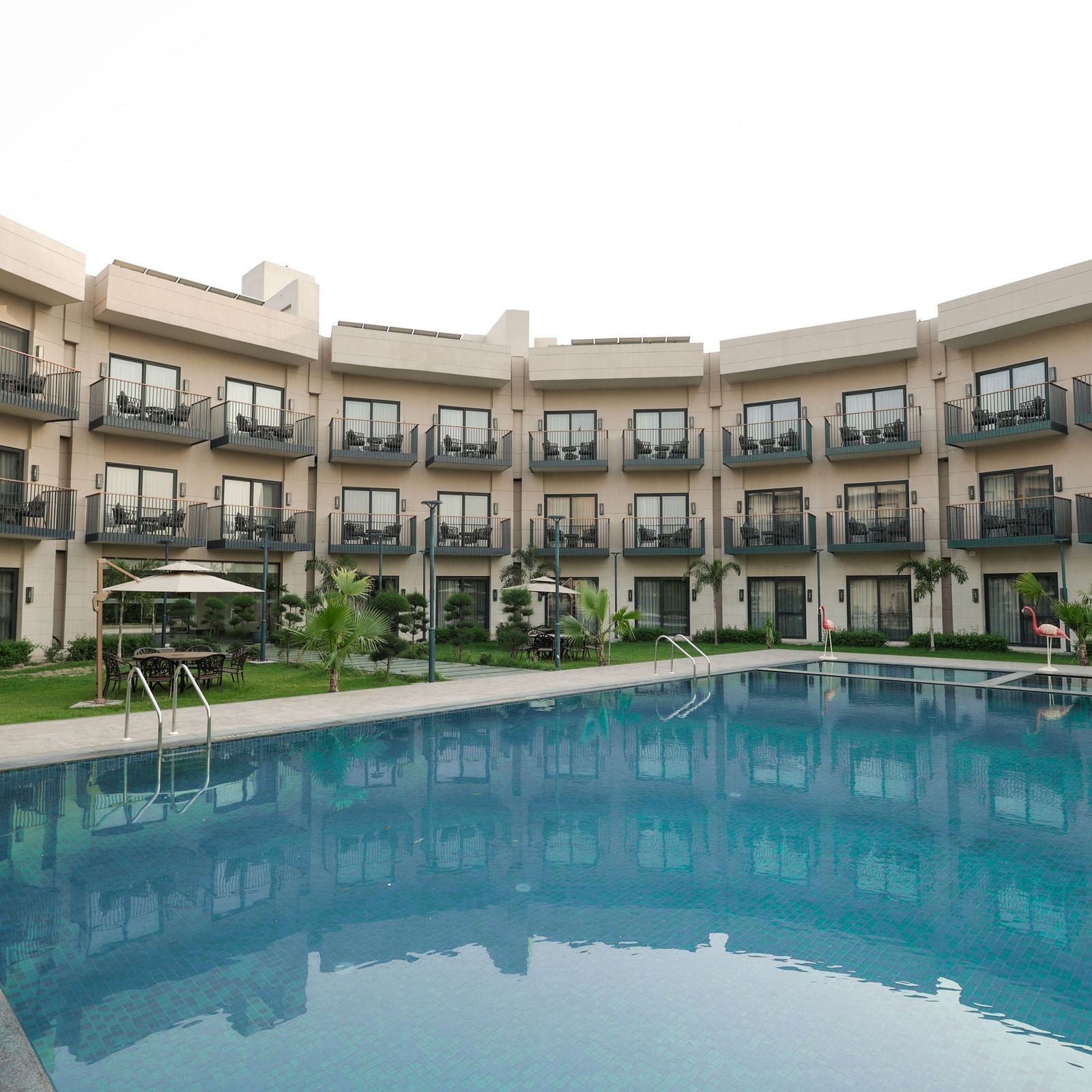 Poolside view of the hotel's courtyard and room balconies at Ramada by Wyndham Sonipat Murthal
