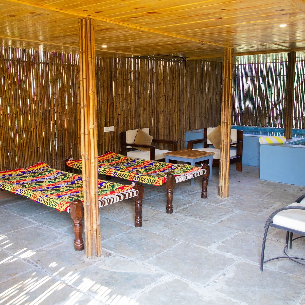 Charpoys and chairs under a thatched roof