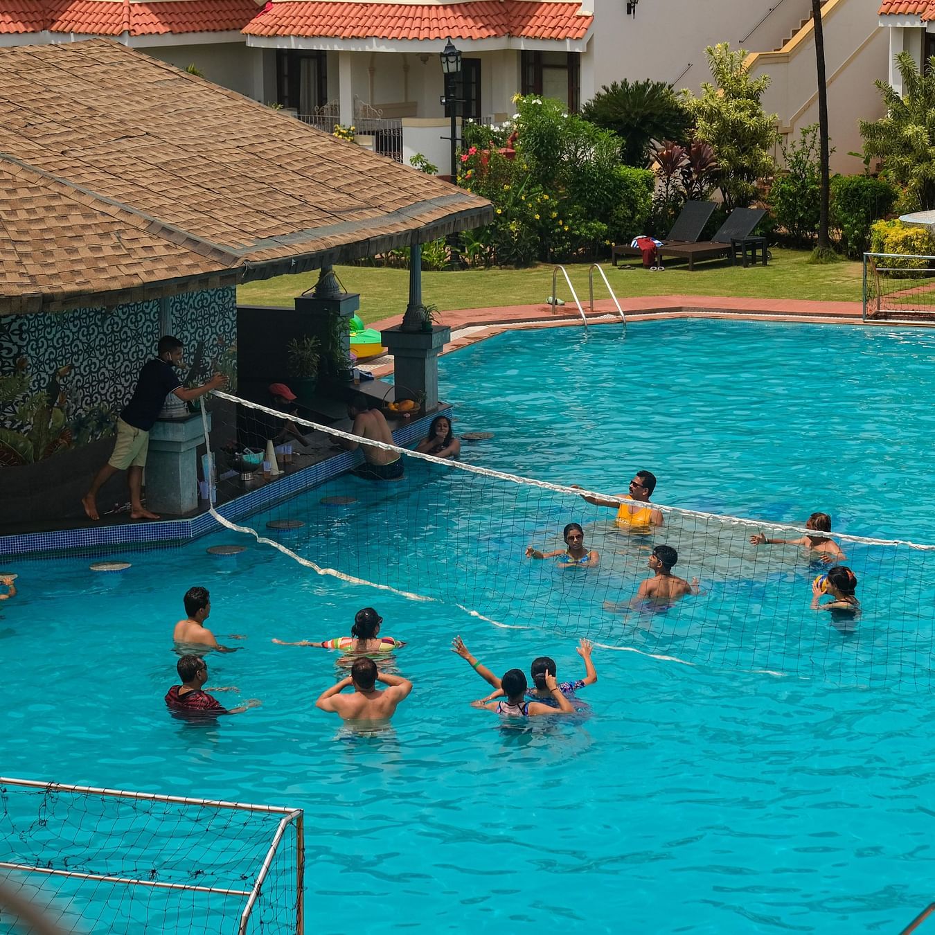 Heritage Village Goa - People playing throwball in the swimming pool while the lifeguard is on duty