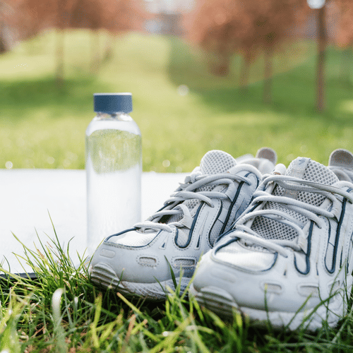 A water bottle and trainers rest on the grass.
