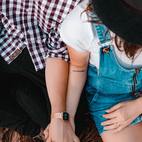 Two people sitting in  a surface, holding hands.