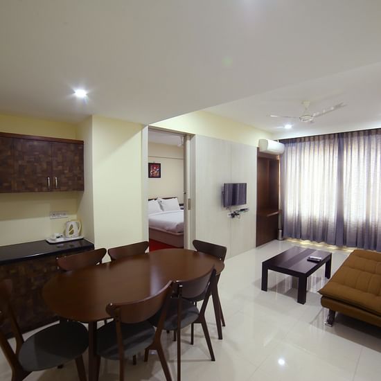 A living area featuring a sofa a table kitchen counter and a dining area - Mysore Gate Hotel Bangalore