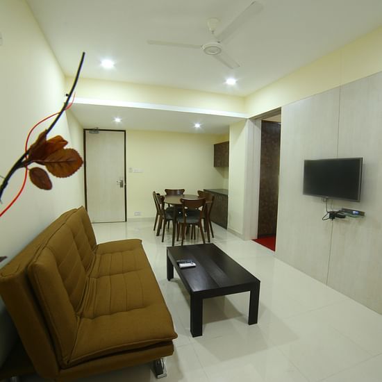 A living space featuring a TV a sofa a table and a dining area - Myore Gate Hotel Bangalore