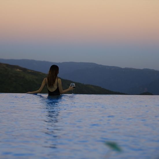 a guest looking out over the infinity swimming pool - Polo Orchid Resort, Cherrapunji