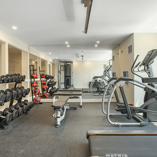 A gym room with equipment to work out including dumbbells and tradmill