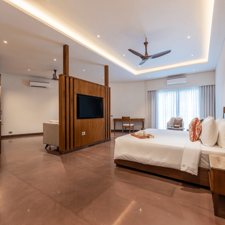 A bedroom with partition, on one side there is a bed and on the other there is a seating area with sofa and table - Ananta Spa and Resort, Ajabgarh