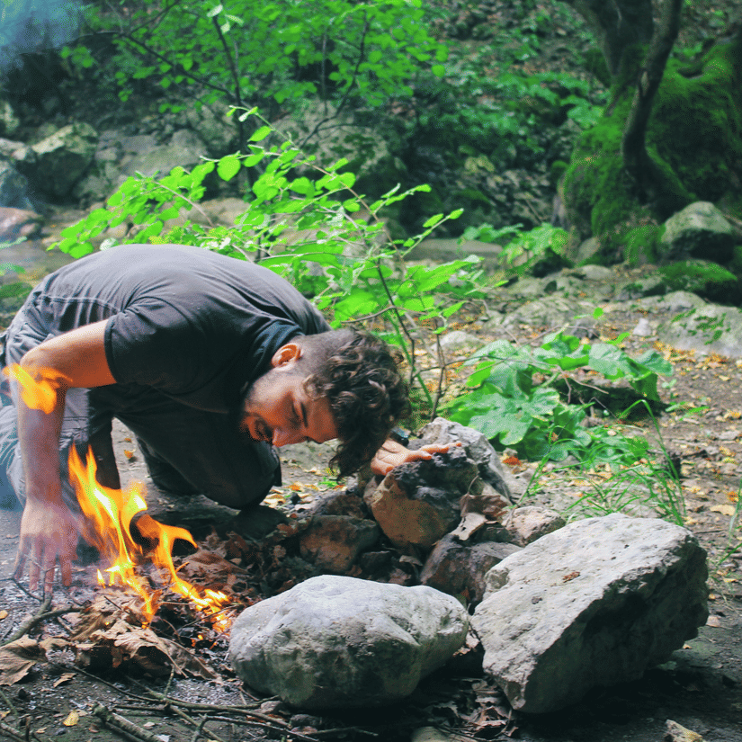 A person is cooking over a fire outdoors using stones.